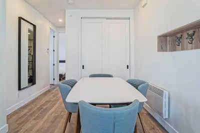 a dining room with a white table and blue chairs at 201 Condo au rez de chaussée , au coeur de Bromont in Bromont