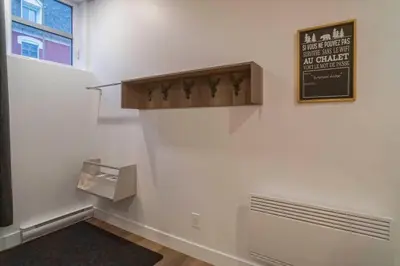 a hallway with a white wall with a sign on it at 883 suite 102 Bromont Vieux Village 2cac , foyer in Bromont