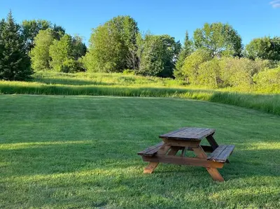 a wooden picnic table sitting in the middle of a field at Magnifique centenaire rénovée, air climatisé, arcade, 3 chambres fermées in Austin