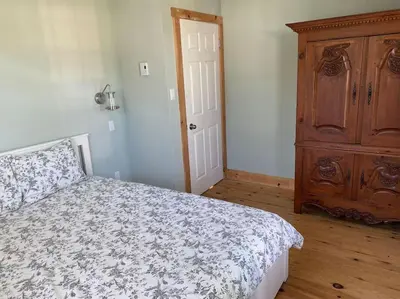 a bedroom with a bed and a wooden dresser at Magnifique centenaire rénovée, air climatisé, arcade, 3 chambres fermées in Austin