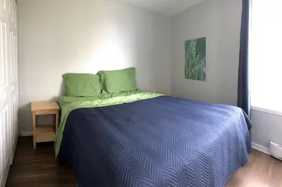 a bedroom with a blue bed with green pillows and a table at La cachette de la rivière au saumon et spa in Scotstown