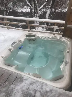 a jacuzzi tub with snow on the ground at La cachette de la rivière au saumon et spa in Scotstown