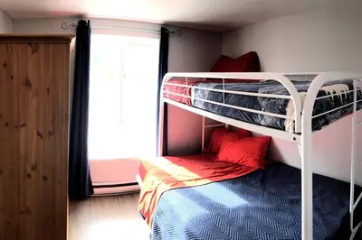 a bedroom with two bunk beds and a window at La cachette de la rivière au saumon et spa in Scotstown