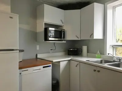 a kitchen with white cabinets and a sink and a microwave at La cachette de la rivière au saumon et spa in Scotstown