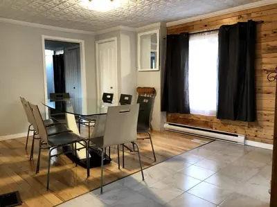a dining room with a glass table and chairs at La cachette de la rivière au saumon et spa in Scotstown