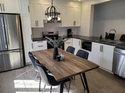 a kitchen with a wooden table with chairs and appliances at Free Parking, Beautiful 4 1/2-2 BR apartment in Montréal