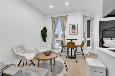 a white living room with a table and chairs at Deluxe Suites Downtown Montreal in Montréal
