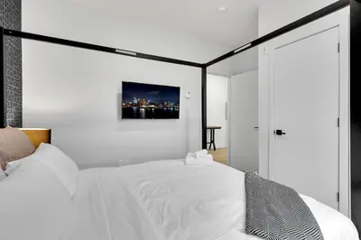 a bedroom with a white bed with a black frame at Deluxe Suites Downtown Montreal in Montréal