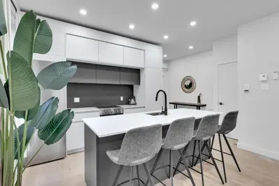 a kitchen with white cabinets and a kitchen island with stools at Deluxe Suites Downtown Montreal in Montréal