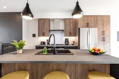 a kitchen with a sink and a counter with chairs at Le Memph Colibri condo cottage eco responsible - hot tub & pool Memphrémagog Lake in Magog-Orford