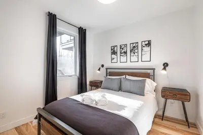 a bedroom with a large bed and a window at Le Memph Colibri condo cottage eco responsible - hot tub & pool Memphrémagog Lake in Magog-Orford