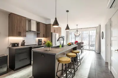 a kitchen with a island with bar stools at Le Memph Colibri condo cottage eco responsible - hot tub & pool Memphrémagog Lake in Magog-Orford