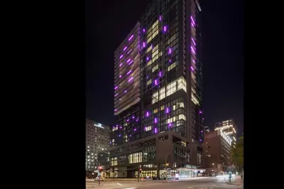 a tall building with purple lights on it at night at HONEYROSE Hotel, Montreal, a Tribute Portfolio Hotel in Montréal