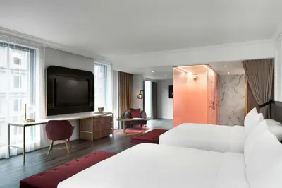 a hotel room with two beds and a flat screen tv at HONEYROSE Hotel, Montreal, a Tribute Portfolio Hotel in Montréal