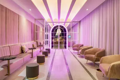 a waiting room with purple walls and tables and chairs at HONEYROSE Hotel, Montreal, a Tribute Portfolio Hotel in Montréal