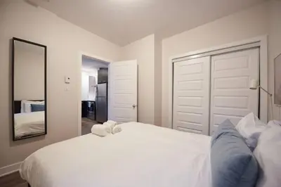 a bedroom with a white bed and a mirror at Design 3 bedroom flat with private terrace in Little Italy by Denstays in Montréal
