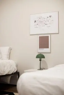 a white bedroom with a bed and a green lamp at Design 3 bedroom flat with private terrace in Little Italy by Denstays in Montréal
