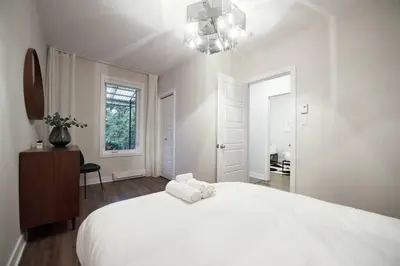 a white bedroom with a large bed and a chandelier at Design 3 bedroom flat with private terrace in Little Italy by Denstays in Montréal