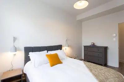 a bedroom with a large white bed with a yellow pillow at Brand New Light filled Mile End Flat by Denstays in Montréal
