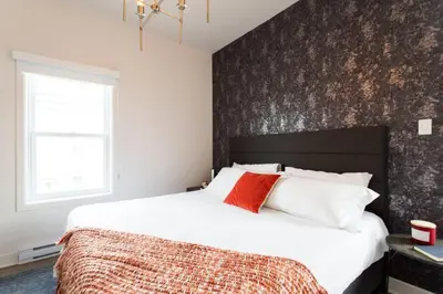a bedroom with a large bed with a black accent wall at Brand New Light filled Mile End Flat by Denstays in Montréal