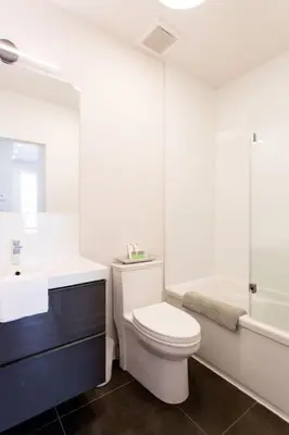 a bathroom with a toilet and a sink and a tub at Brand New Light filled Mile End Flat by Denstays in Montréal