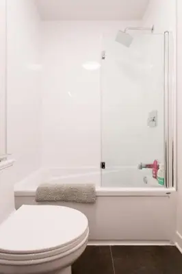a white bathroom with a toilet and a bath tub at Brand New Light filled Mile End Flat by Denstays in Montréal