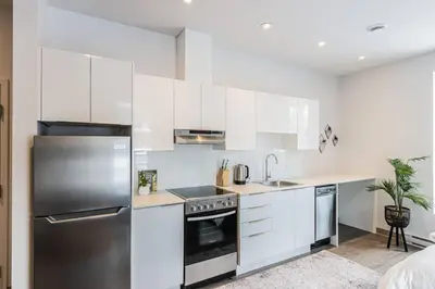 a kitchen with white cabinets and a stainless steel refrigerator at Amazing New Apartment Close to Mount Royal Le Plateau by Denstays in Montréal