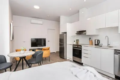 a kitchen with white cabinets and a table and chairs at Amazing New Apartment Close to Mount Royal Le Plateau by Denstays in Montréal