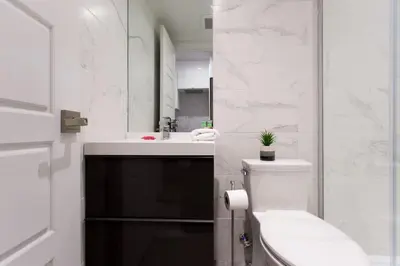a white bathroom with a toilet and a sink at Palms Little Italy Studio with full bathroom by Denstays in Montréal