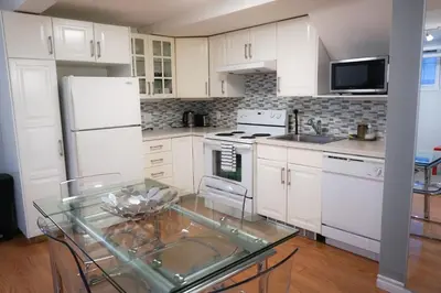 a kitchen with white cabinets and a glass table at Free Parking - Great 1BR near Henri Bourassa Metro in Montréal