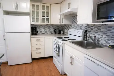 a white kitchen with a sink and a refrigerator at Free Parking - Great 1BR near Henri Bourassa Metro in Montréal