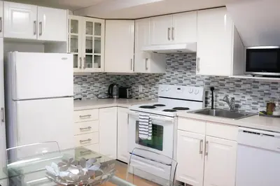 a white kitchen with white appliances and a glass table at Free Parking - Great 1BR near Henri Bourassa Metro in Montréal