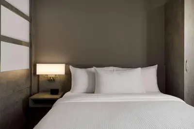 a bed with white pillows in a bedroom with a lamp at Microtel Inn & Suites by Wyndham Boisbriand in Sainte-Thérèse-de-Blainville