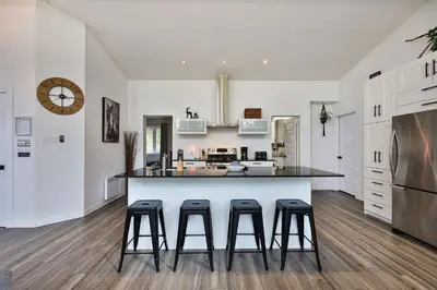 a kitchen with a large island with bar stools at Chalet Le Cerf du Lac in Disraeli