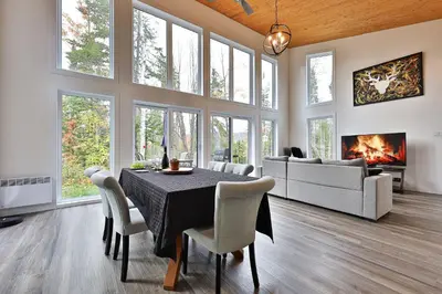 a dining room with a table and a fireplace at Chalet Le Cerf du Lac in Disraeli