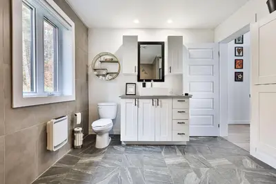 a white bathroom with a toilet and a mirror at Chalet Le Cerf du Lac in Disraeli