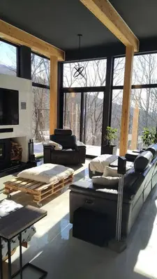a living room with couches and tables and windows at Magnifique Chalet En Montagne in Shefford