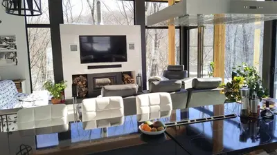 a living room with white chairs and a flat screen tv at Magnifique Chalet En Montagne in Shefford