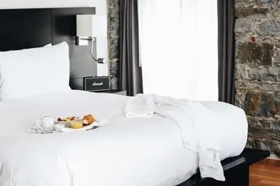 a white bed with a plate of food on it at Le Petit Hotel Notre Dame in Montréal