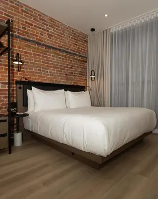 a bedroom with a large bed with a brick wall at Le Petit Hotel Notre Dame in Montréal