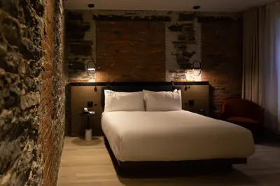 a bedroom with a large white bed and a brick wall at Le Petit Hotel Notre Dame in Montréal