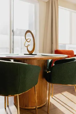 a dining room table with green chairs and a sculpture at Rozenhaus Hotel Montreal in Montréal