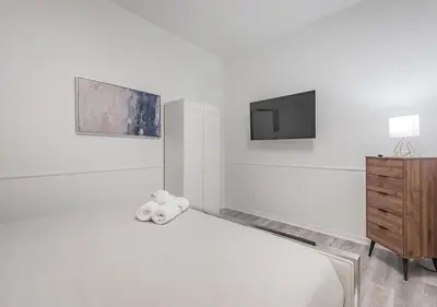 a white room with a bed and a tv at Luxurious 3BD Apt in heart of downtown 5 min walk to Bell Center in Montréal