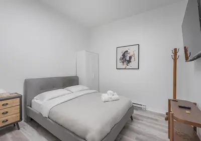 a white bedroom with a bed and a dresser at Luxurious 3BD Apt in heart of downtown 5 min walk to Bell Center in Montréal
