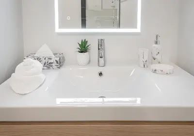 a white bathroom with a sink and a mirror at Luxurious 3BD Apt in heart of downtown 5 min walk to Bell Center in Montréal