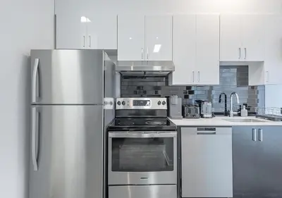 a kitchen with stainless steel appliances and white cabinets at Luxurious 3BD Apt in heart of downtown 5 min walk to Bell Center in Montréal