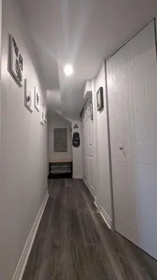 a hallway with white walls and wooden floors and white doors at Simplement l’Harmonie à Chambly in Chambly