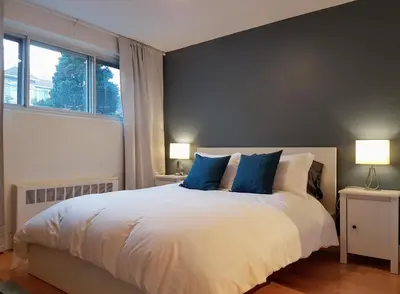 a bedroom with a large white bed with blue pillows at Bright and Spacious Studio Apartment in Montréal