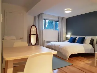 a bedroom with a bed and a table and a mirror at Bright and Spacious Studio Apartment in Montréal