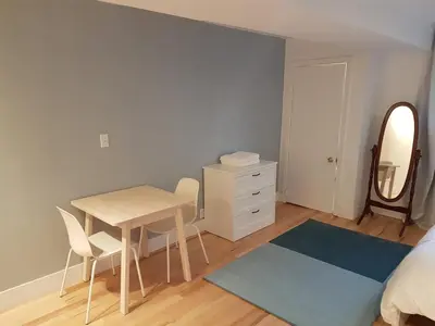 a bedroom with a table and chairs and a mirror at Bright and Spacious Studio Apartment in Montréal